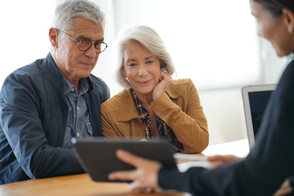 A senior couple reviewing Medicare enrollment options with their advisor on a tablet